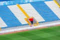 Field of empty white and blue seats, yellow stairs, gate exit on the stadium corner