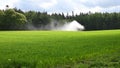 A field of a farmer is moistened with water by a large sprinkler