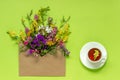 Field flowers in craft envelope and cup of herbs tea