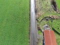 A field of grass grown for hay with a road cutting through it and a barn Royalty Free Stock Photo