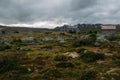 field with grass and stones with houses under stormy sky, Norway, Hardangervidda Royalty Free Stock Photo