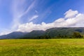 Blue sky with white clouds and field with green grass in the for Royalty Free Stock Photo