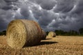 Field with hay bales under stormy sky and rays of light Royalty Free Stock Photo