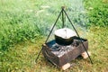 Field kitchen. The pot on the fire. Cooking the soup outdoors in the mountains, waiting for the eating