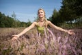 A beautiful young herbalist spreads her arms wide and embraces the heather flowers. Field herbs.