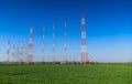 A field with radio and electricity antennas towers with blue sky and green grass landscape Royalty Free Stock Photo