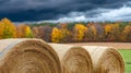 In a field, a straw bale is captured up close under a dramatic sky illuminated by soft sunlight Royalty Free Stock Photo