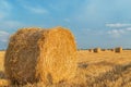 Field with straw bales after harvest with cloudy sky in sunset t Royalty Free Stock Photo