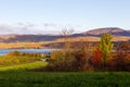 Field and trees in the Fall, with the St. Lawrence River and the Laurentian mountains in soft focus background Royalty Free Stock Photo