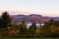 Field and trees in the Fall, with the St. Lawrence River and the Ste. Anne-de-Beaupre basilica at the foot of the Laurentian mount