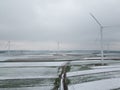 Field troga among windmills on the first snowy day. Top view, sky background in fog Royalty Free Stock Photo