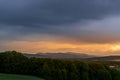 A field of wheat and a view of dark clouds on a hilly landscape before sunset in the distance you can see the rain Royalty Free Stock Photo