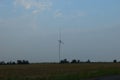 A field of windmills spin in front of a colorful evening sky. A wind turbine is used to produce electricity. Wind energy is the Royalty Free Stock Photo