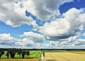 Fields, meadows, trees and a country lane in the lowlands of northern Germany under a white blue cloudy sky, aerial view Royalty Free Stock Photo