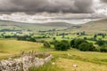 Fields and sheep on farm land in a valley with rain clouds