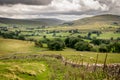 Fields and sheep on farm land in a valley with rain clouds