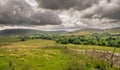 Fields and sheep on farm land in a valley with rain clouds