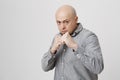 Fierce and confident stylish european bald bearded male model in gray shirt holding fists in front of him as if ready
