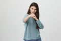 Fierce and confident stylish european young female in blue loose sweater with long dark hair holding fists in front of