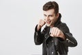 Fierce and confident young handsome man in black leather jacket holding fists in front of him as if ready for fight or Royalty Free Stock Photo