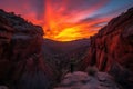 fiery canyon sunset, with a silhouetted person standing on the rim of the canyon
