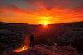 fiery canyon sunset, with a silhouetted person standing on the rim of the canyon