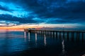 Fiery cloud and sky over the sea at sunset with a pier Royalty Free Stock Photo