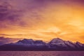 A fiery dawn over the snowy peaks of the fjord