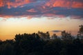 Fiery evening sunset, orange-blue color. On the horizon are silhouettes of houses and trees. Landscape, hectic clouds