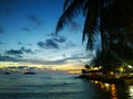 Fiery glow sunset over a beautiful tropical beach and ocean water. Different colours of clouds and the silhouette of palm tree. Royalty Free Stock Photo