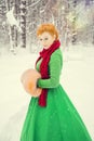 Fiery red-haired woman in a ball green dress with a red leather belt in the costume of dwarf assistant Santa Claus in the winter f