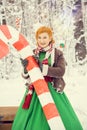 Fiery red-haired woman in a ball green dress with a red leather belt in the costume of dwarf assistant Santa Claus in