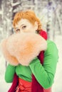 Fiery red-haired woman in a ball green dress with a red leather belt in the costume of dwarf assistant Santa Claus in the winter f