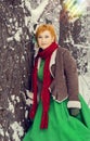 Fiery red-haired woman in a ball green dress with a red leather belt in the costume of dwarf assistant Santa Claus in the winter f