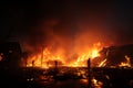 Fiery silhouette, firemen wrestle towering scrap blaze