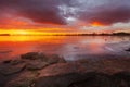 Fiery Sunrise over a Frozen Winter Lake with Rocks in the Foreground Royalty Free Stock Photo