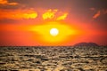 fiery sunset over ocean, with vibrant shades of orange and red painting sky. sun sets dramatically, casting warm glow on dark Royalty Free Stock Photo