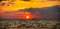 fiery sunset over ocean, with vibrant shades of orange and red painting sky. sun sets dramatically, casting warm glow on dark