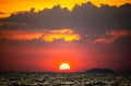 fiery sunset over ocean, with vibrant shades of orange and red painting sky. sun sets dramatically, casting warm glow on dark Royalty Free Stock Photo