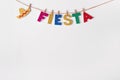 Fiesta word on pins against white wall background. Fragment of festive DIY decoration of interior. Cinco de mayo celebration Royalty Free Stock Photo