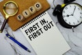 FIFO First-In, First-Out text written on notepad with magnifying glass and alarm clock on marble background Royalty Free Stock Photo