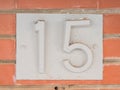 Fifteen house number placed on the brick wall. Royalty Free Stock Photo