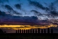 Fifteen moai against orange and blue sunrise