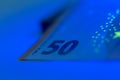 Close-up of a fifty euro banknote under blue light highlighting its security features Royalty Free Stock Photo