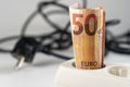A fifty euro banknote is plugged into a power strip. Close-up. Extension socket