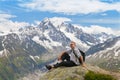 Fifty years tourists sitting on a rock against mountain summits Royalty Free Stock Photo