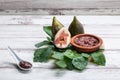 Fig jam with figs, fig leaves and white spoon with jam on .white wooden   background Royalty Free Stock Photo