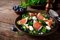 Fig salad with goat cheese, blueberry, walnuts and arugula on wooden background. Healthy food. Lunch Royalty Free Stock Photo