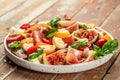 Fig salad with prosciutto, mozzarella, fresh basil leaves and tomato on a wooden background