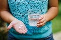 Fight against severe headache, girl holds a glass of clean water and two white pills Royalty Free Stock Photo